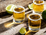 Small salt-rimmed glassed of spirits and wedges of lime on a table