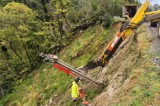Road worker down bank with machinery