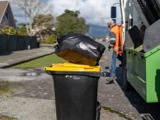 Recycling bin with rubbish bag on top close up