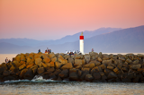 Rock wall on river mouth with lighthouse on it with sunset in the background