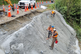 Contractors spraying concrete on a road embankment