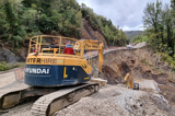 Excavator working a roadside slip