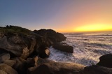 View out at sunset over the ocean from a rocky shore