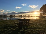 A park bench overlooking an estuary with the sun setting in the background